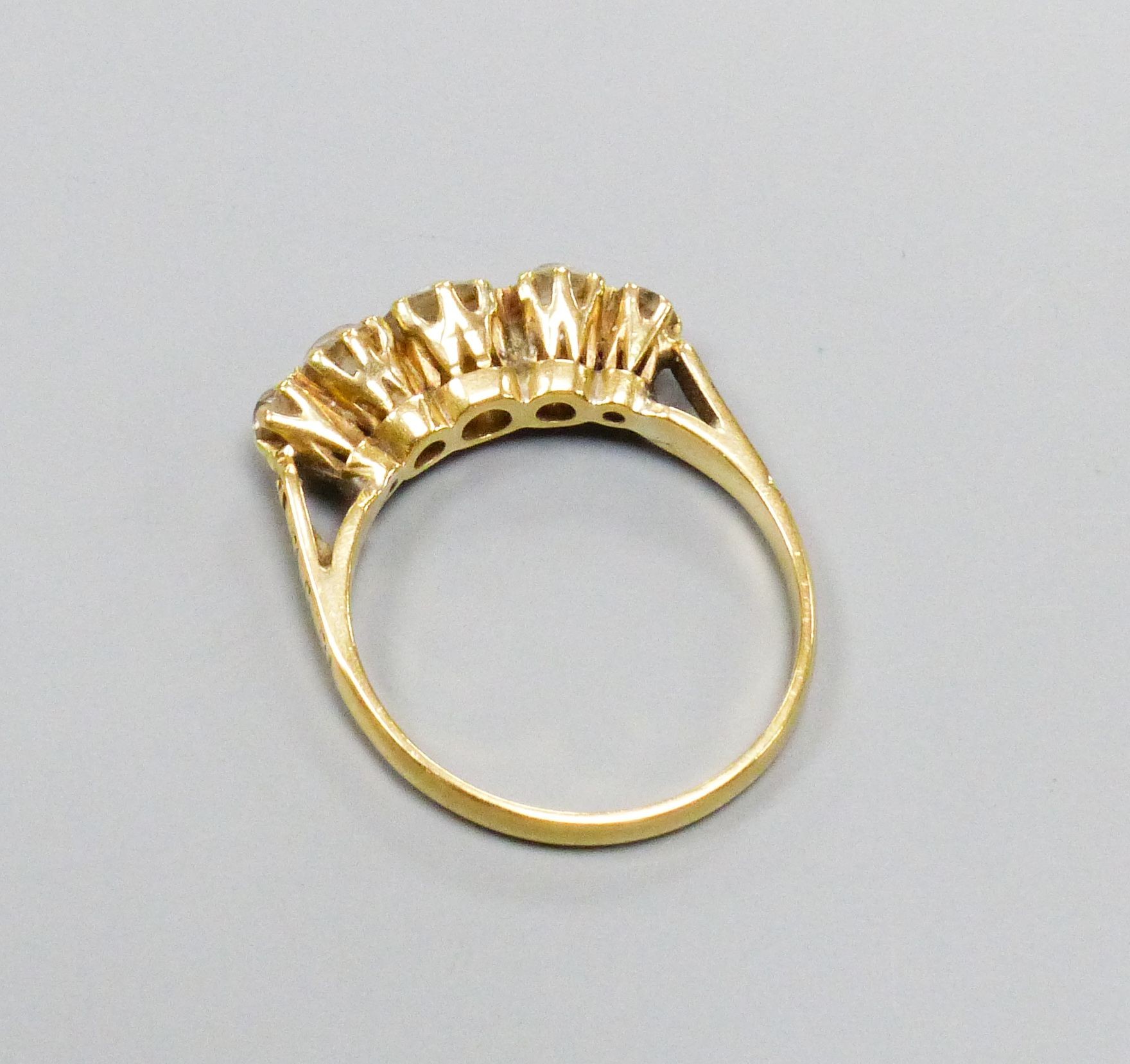 A five-stone diamond ring, yellow metal setting, claw-set with carved shoulders, size N, gross 3 grams.